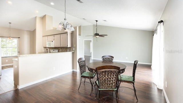 dining space featuring vaulted ceiling, dark hardwood / wood-style flooring, sink, and ceiling fan with notable chandelier