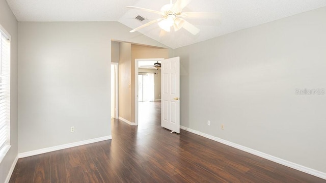 spare room featuring dark wood-type flooring, vaulted ceiling, and plenty of natural light