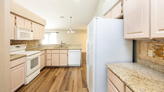 kitchen featuring white appliances, decorative light fixtures, sink, backsplash, and a notable chandelier