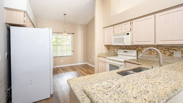 kitchen with pendant lighting, white appliances, sink, backsplash, and kitchen peninsula