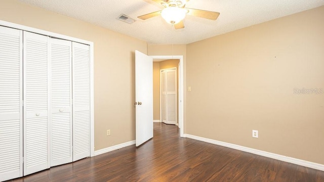 unfurnished bedroom with ceiling fan, a textured ceiling, dark hardwood / wood-style floors, and a closet