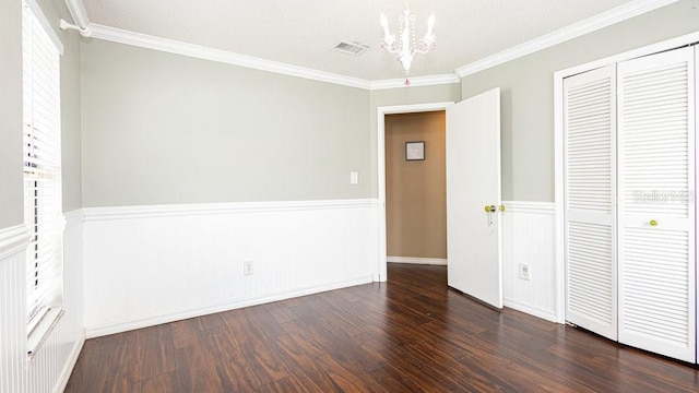 unfurnished bedroom featuring a closet, ornamental molding, dark hardwood / wood-style flooring, and an inviting chandelier