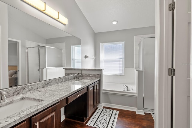 bathroom with vaulted ceiling, shower with separate bathtub, hardwood / wood-style flooring, and vanity