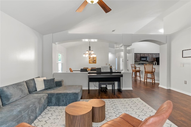 living room with vaulted ceiling, dark hardwood / wood-style flooring, and ceiling fan with notable chandelier