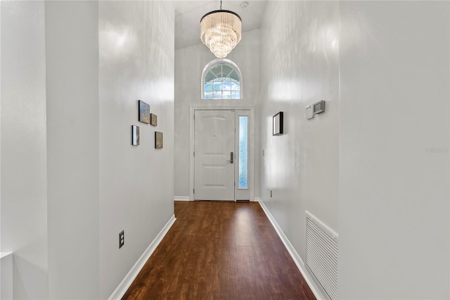 entrance foyer with a towering ceiling, dark hardwood / wood-style floors, and a notable chandelier