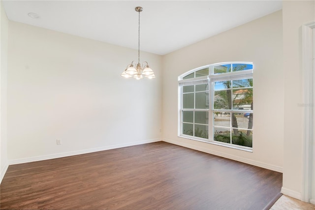 empty room with hardwood / wood-style floors and an inviting chandelier