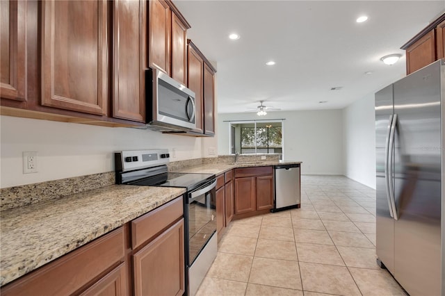 kitchen with ceiling fan, sink, light tile patterned flooring, stainless steel appliances, and light stone counters