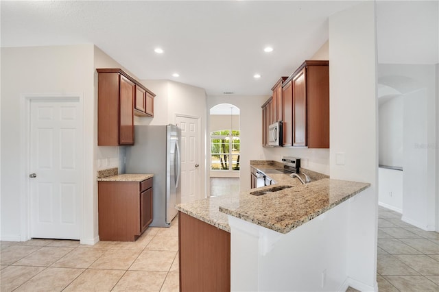 kitchen featuring light tile patterned floors, kitchen peninsula, stainless steel appliances, light stone counters, and sink