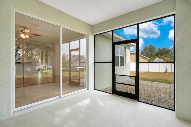 unfurnished sunroom featuring ceiling fan and plenty of natural light