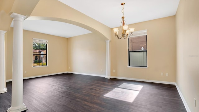 empty room with decorative columns, dark hardwood / wood-style floors, and a notable chandelier