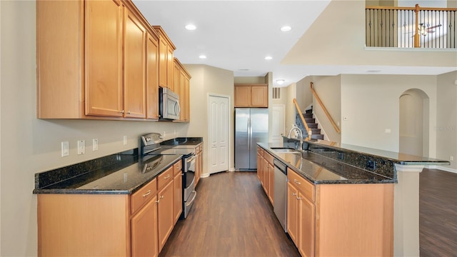 kitchen featuring sink, dark wood-type flooring, dark stone countertops, and appliances with stainless steel finishes