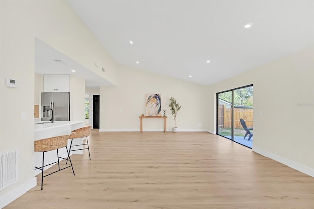 living room with high vaulted ceiling and light wood-type flooring