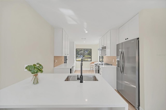 kitchen featuring sink, white cabinetry, stainless steel appliances, decorative backsplash, and kitchen peninsula