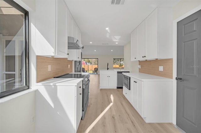 kitchen featuring wall chimney exhaust hood, appliances with stainless steel finishes, tasteful backsplash, and white cabinets