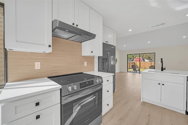 kitchen with lofted ceiling, sink, white cabinetry, light hardwood / wood-style flooring, and appliances with stainless steel finishes