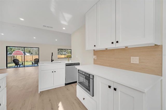 kitchen featuring built in microwave, sink, white cabinetry, stainless steel dishwasher, and light hardwood / wood-style floors