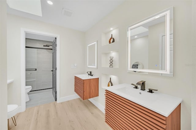 bathroom with vanity, toilet, a shower with door, and hardwood / wood-style floors