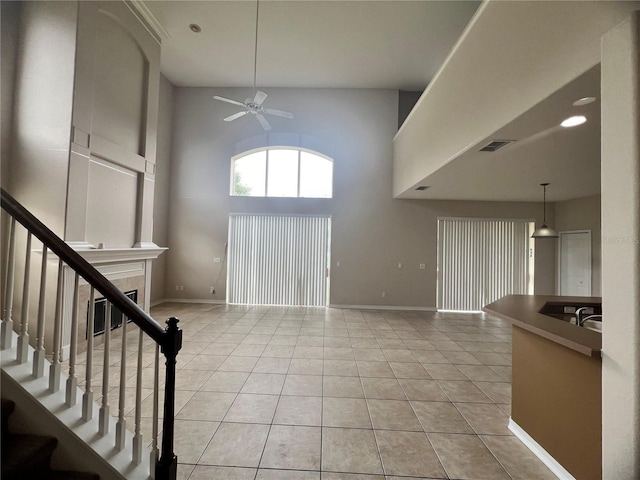 tiled foyer with ceiling fan and a high ceiling