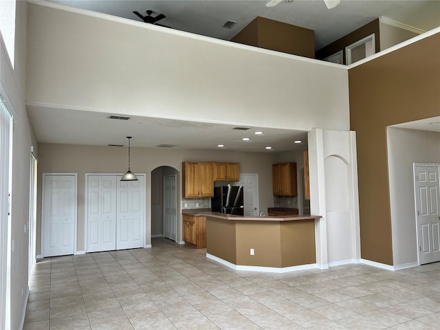 kitchen featuring ceiling fan, kitchen peninsula, hanging light fixtures, black refrigerator, and light tile patterned floors