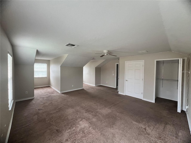 additional living space featuring ceiling fan, a textured ceiling, vaulted ceiling, and dark colored carpet