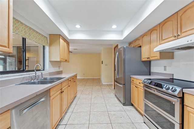 kitchen with light tile patterned floors, stainless steel appliances, a raised ceiling, light brown cabinetry, and sink