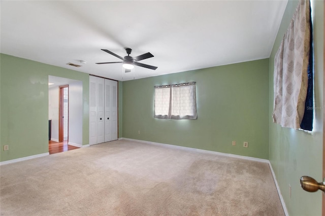 unfurnished bedroom featuring ceiling fan, light carpet, and a closet