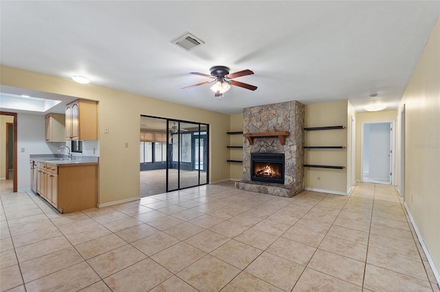 unfurnished living room with ceiling fan, light tile patterned floors, a fireplace, and sink