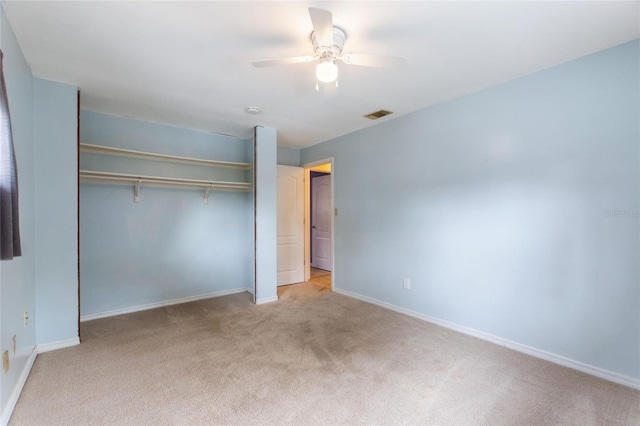 unfurnished bedroom featuring ceiling fan, a closet, and light carpet