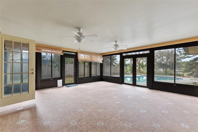 unfurnished sunroom featuring ceiling fan and french doors