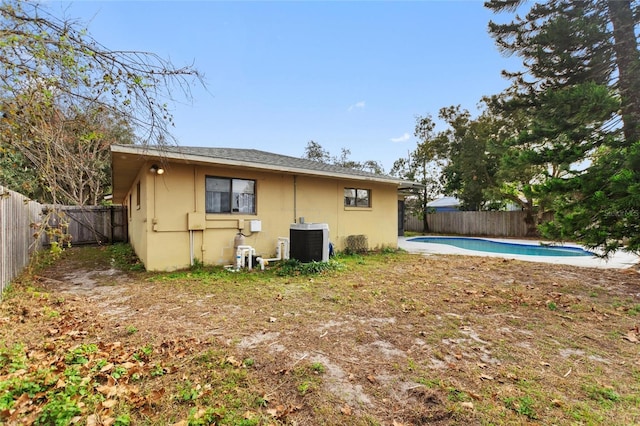 rear view of house featuring cooling unit and a fenced in pool