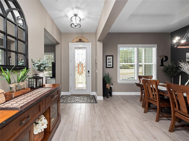 foyer entrance with light hardwood / wood-style floors and a notable chandelier