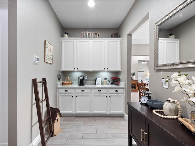 kitchen featuring light wood-type flooring, white cabinetry, and light stone countertops