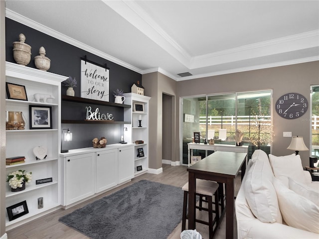 living room featuring hardwood / wood-style floors, a raised ceiling, and crown molding