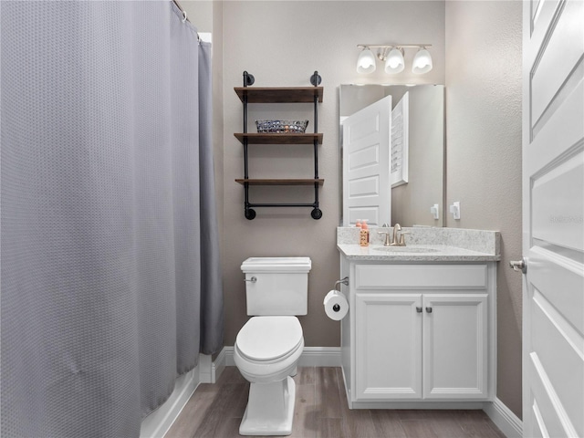 bathroom with toilet, vanity, and hardwood / wood-style floors