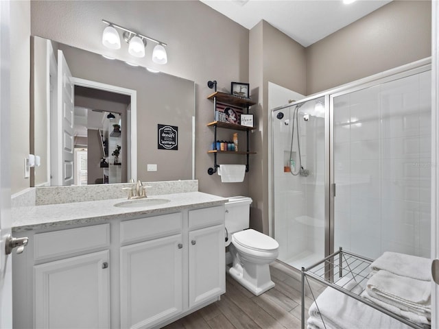 bathroom featuring a shower with shower door, toilet, and vanity