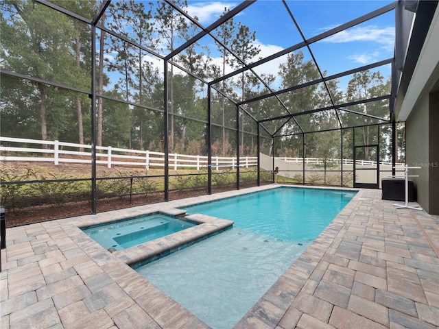 view of swimming pool with glass enclosure, a patio area, and an in ground hot tub