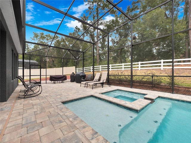 view of pool with an in ground hot tub, glass enclosure, and a patio