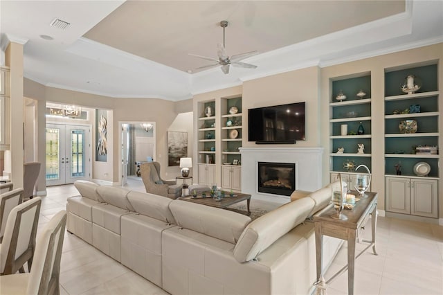 living room featuring light tile patterned floors, ceiling fan, a tray ceiling, french doors, and built in shelves