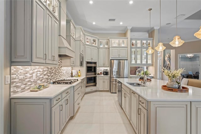 kitchen featuring appliances with stainless steel finishes, pendant lighting, backsplash, and an island with sink