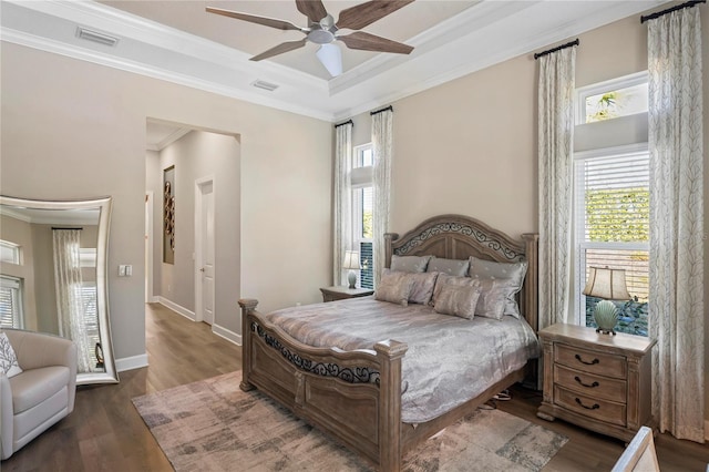 bedroom with ceiling fan, ornamental molding, dark hardwood / wood-style floors, and a tray ceiling