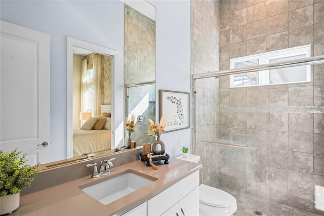 bathroom featuring toilet, vanity, and a shower with shower door