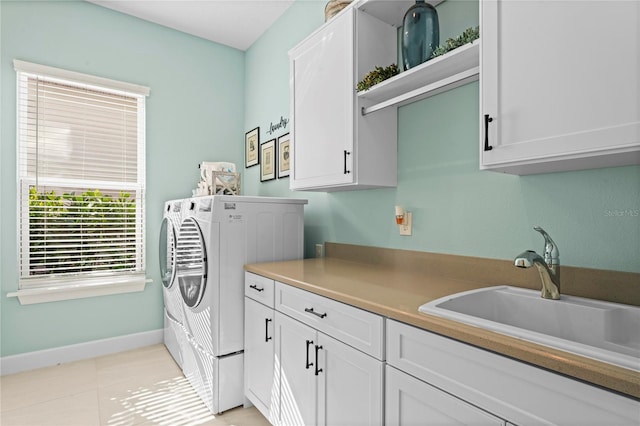 laundry room with cabinets, sink, light tile patterned flooring, and washing machine and clothes dryer