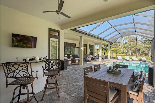 view of patio featuring ceiling fan and glass enclosure