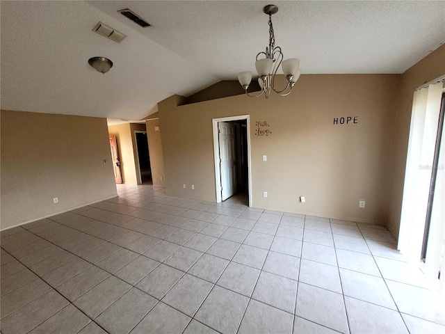 tiled spare room with lofted ceiling and a notable chandelier