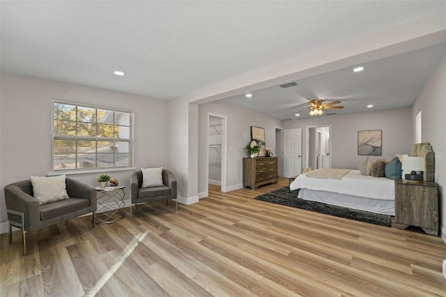 bedroom featuring ceiling fan, a spacious closet, a closet, and light hardwood / wood-style flooring