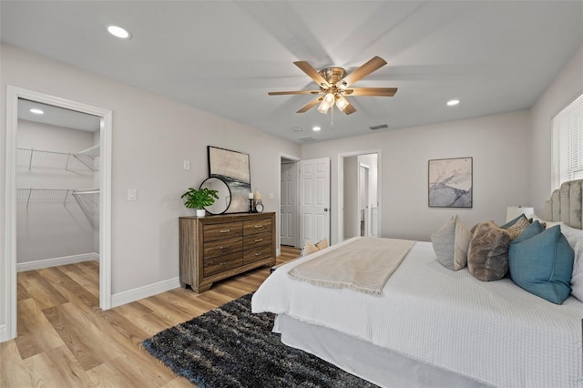 bedroom featuring ceiling fan, a walk in closet, a closet, and light hardwood / wood-style floors