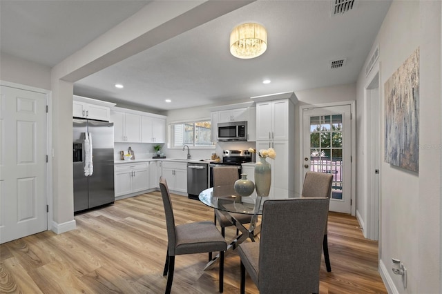 dining room featuring light hardwood / wood-style floors, sink, and a healthy amount of sunlight