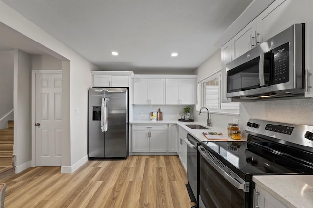 kitchen with stainless steel appliances, decorative backsplash, white cabinets, and sink