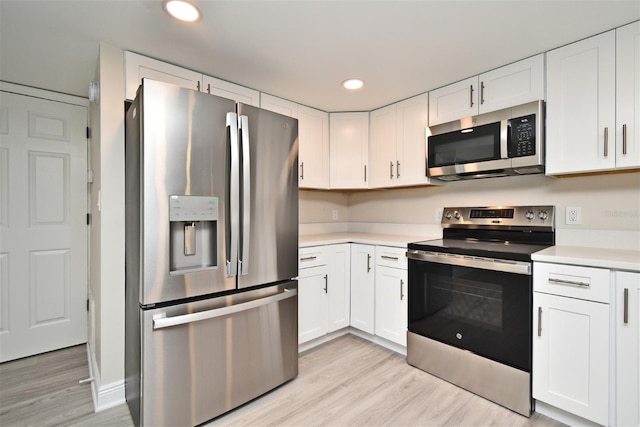 kitchen with white cabinets, stainless steel appliances, and light wood-type flooring