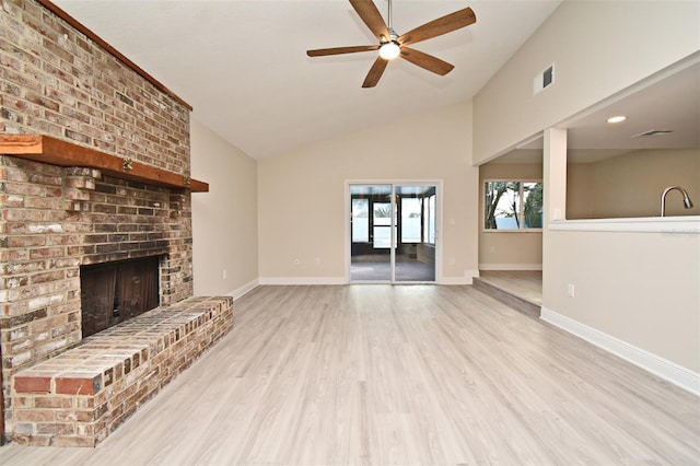 unfurnished living room with lofted ceiling, light wood-type flooring, a fireplace, and ceiling fan